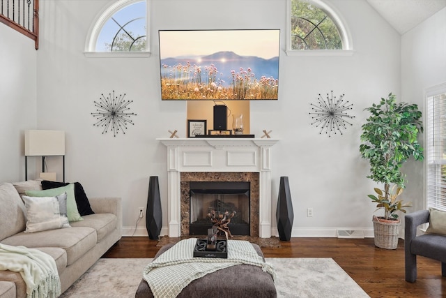 living room with hardwood / wood-style floors, a high end fireplace, and lofted ceiling