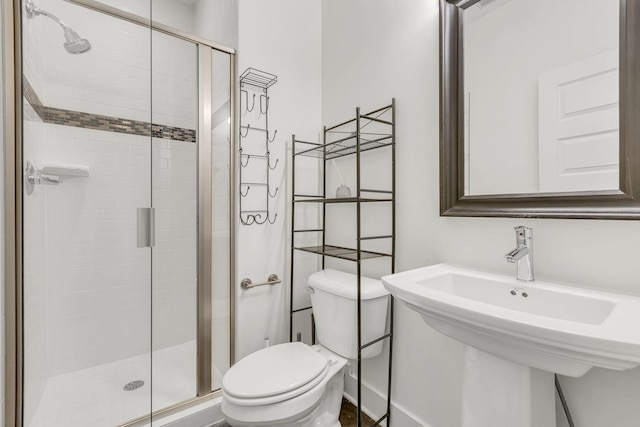 bathroom featuring toilet, an enclosed shower, and sink