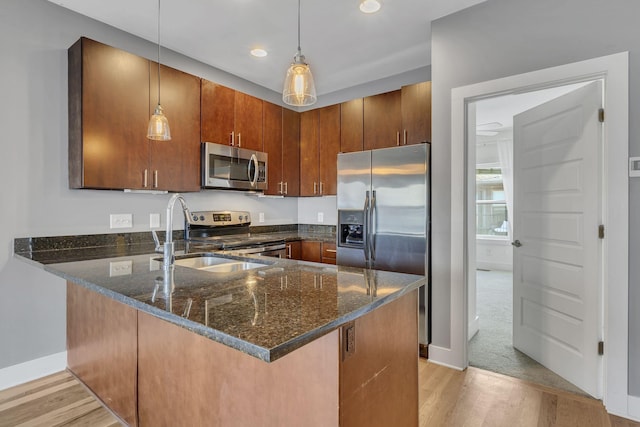 kitchen with dark stone counters, pendant lighting, stainless steel appliances, and sink