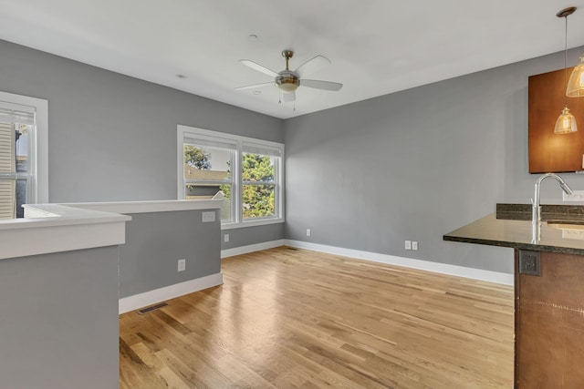 unfurnished living room with ceiling fan, sink, and light hardwood / wood-style flooring