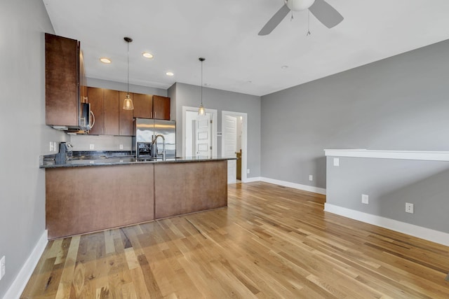 kitchen with appliances with stainless steel finishes, light wood-type flooring, ceiling fan, sink, and decorative light fixtures