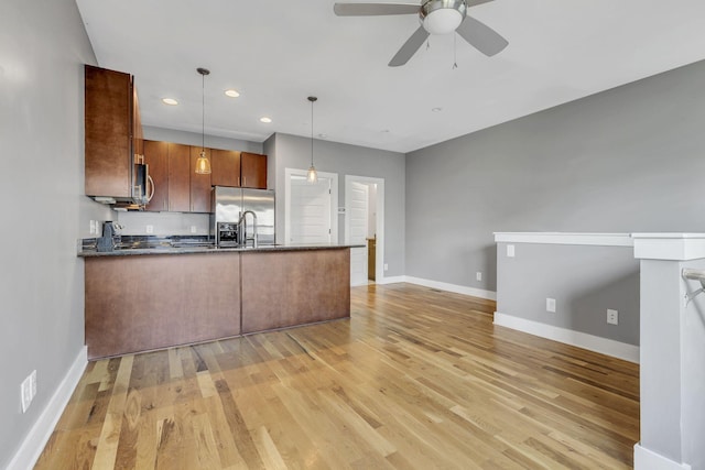 kitchen with kitchen peninsula, appliances with stainless steel finishes, light wood-type flooring, ceiling fan, and decorative light fixtures