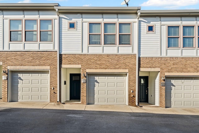 townhome / multi-family property featuring a garage and brick siding