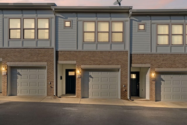 multi unit property featuring a garage and brick siding