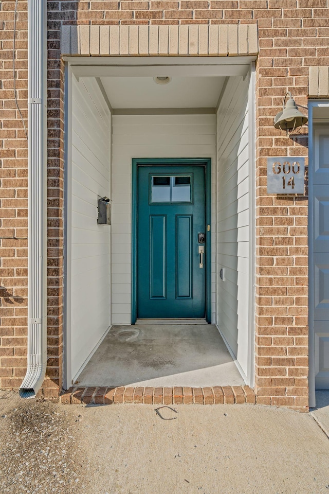 entrance to property with a garage and brick siding