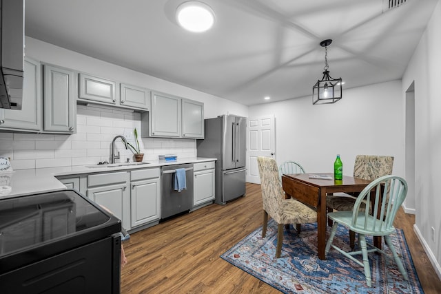 kitchen with gray cabinets, decorative backsplash, sink, dark wood-type flooring, and stainless steel appliances