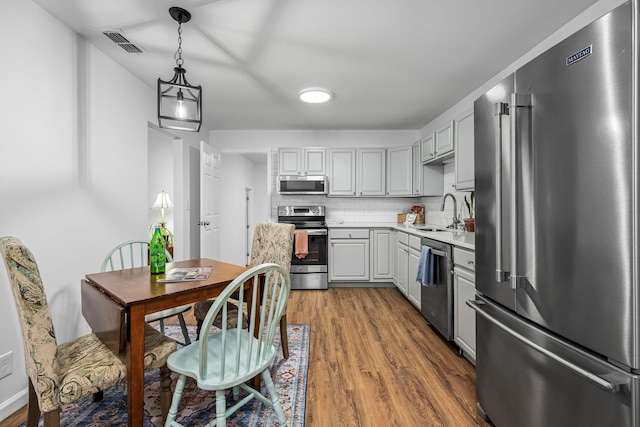 kitchen with hardwood / wood-style floors, appliances with stainless steel finishes, gray cabinetry, and tasteful backsplash