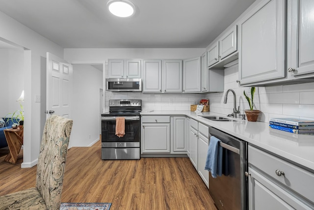 kitchen with appliances with stainless steel finishes, decorative backsplash, dark hardwood / wood-style floors, and sink