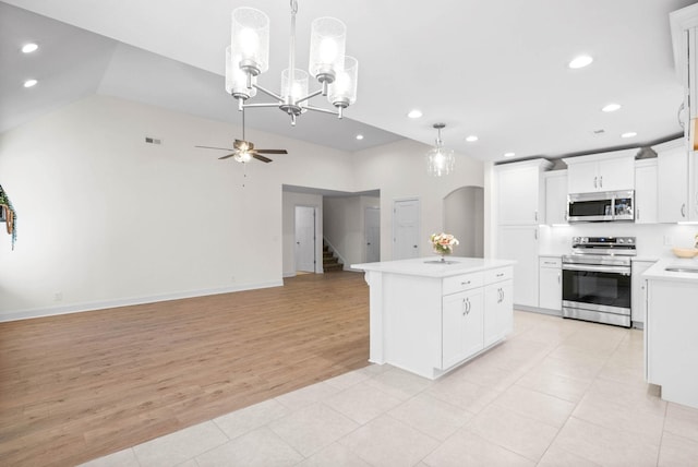 kitchen with pendant lighting, a kitchen island, light tile patterned floors, stainless steel appliances, and white cabinets