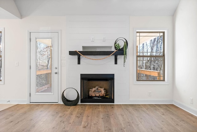 unfurnished living room featuring a large fireplace, light hardwood / wood-style flooring, and vaulted ceiling