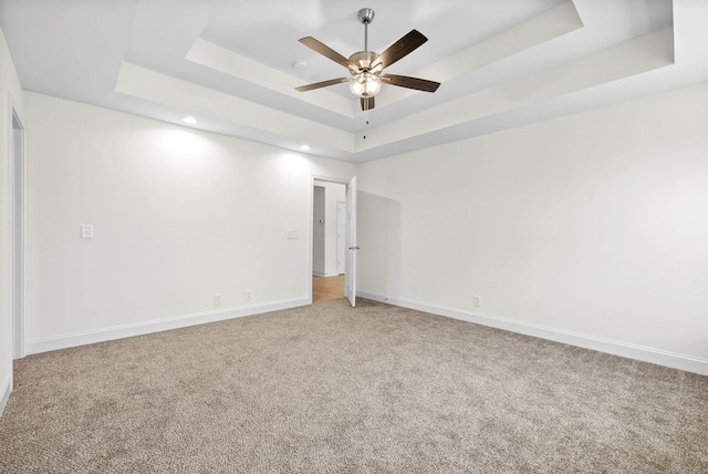 carpeted spare room with ceiling fan and a tray ceiling