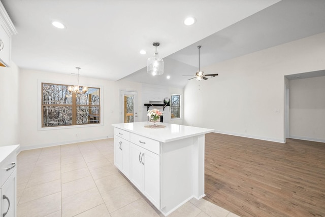 kitchen featuring a kitchen island, pendant lighting, ceiling fan with notable chandelier, and white cabinetry