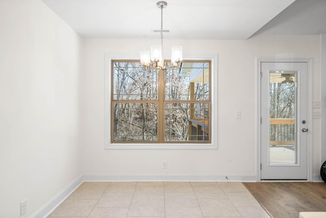 unfurnished dining area featuring light tile patterned floors and a notable chandelier