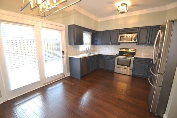 kitchen with sink, backsplash, dark hardwood / wood-style flooring, ornamental molding, and stainless steel appliances