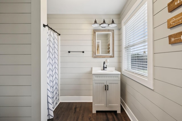 bathroom with a shower with curtain, wooden walls, hardwood / wood-style floors, and vanity