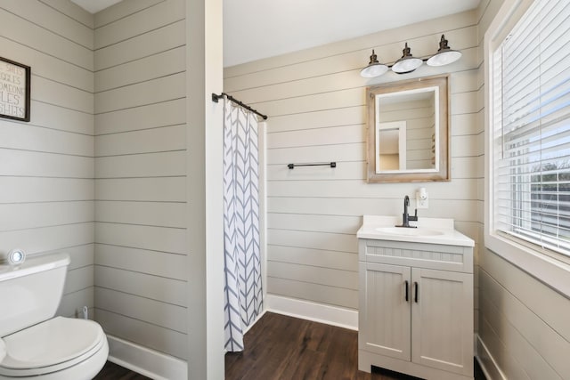 bathroom featuring wood walls, wood-type flooring, toilet, vanity, and a shower with shower curtain