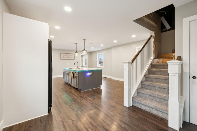 kitchen featuring dark hardwood / wood-style floors, decorative light fixtures, a kitchen island with sink, and sink