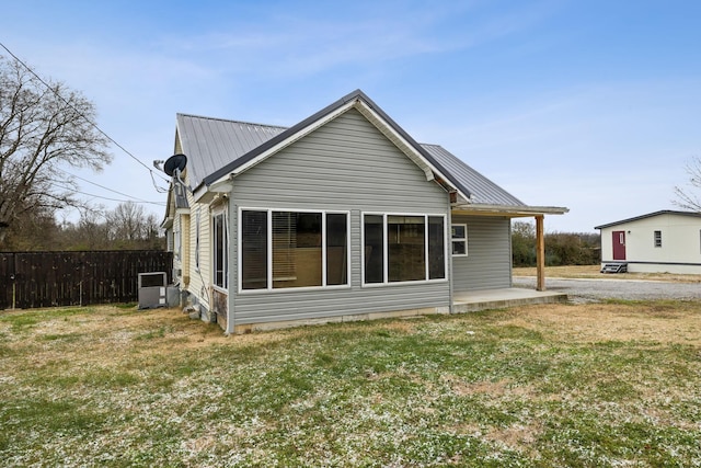 rear view of property with a yard and central air condition unit