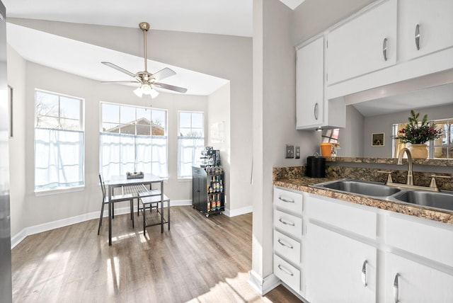 kitchen featuring vaulted ceiling, ceiling fan, sink, light hardwood / wood-style flooring, and white cabinetry