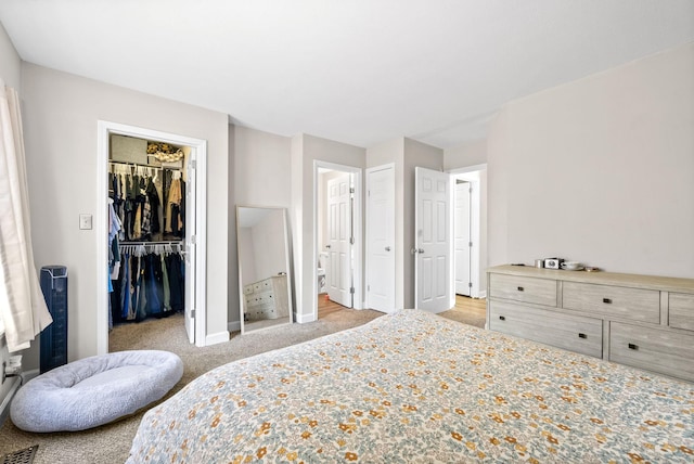 bedroom with a walk in closet, light carpet, and a closet