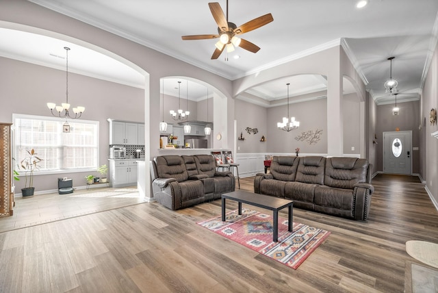 living room with ceiling fan, a towering ceiling, wood-type flooring, and ornamental molding