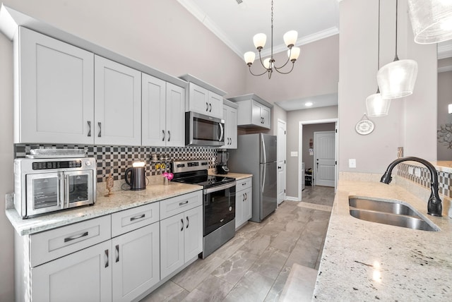 kitchen featuring sink, hanging light fixtures, light stone countertops, stainless steel appliances, and a chandelier