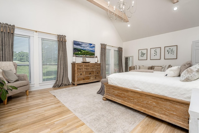 bedroom featuring wood-type flooring, high vaulted ceiling, and an inviting chandelier