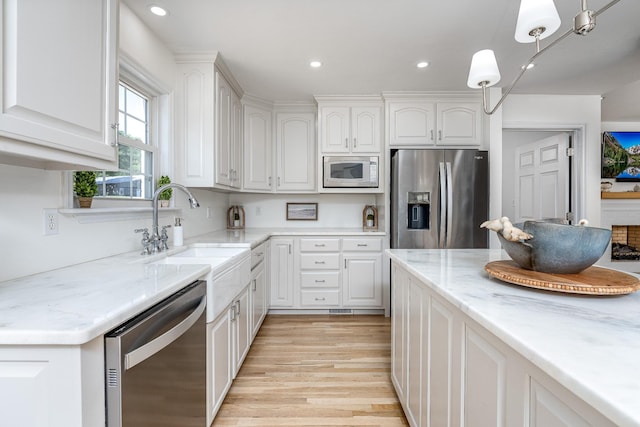 kitchen featuring white cabinets, pendant lighting, stainless steel appliances, and sink