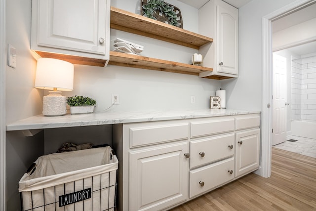 interior space featuring white cabinetry, light stone counters, and light hardwood / wood-style floors