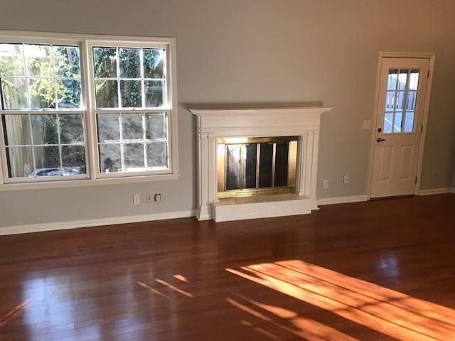 unfurnished living room with a wealth of natural light and dark hardwood / wood-style flooring