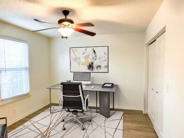 home office with light hardwood / wood-style flooring and ceiling fan