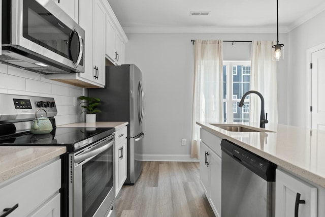 kitchen with light stone countertops, stainless steel appliances, sink, decorative light fixtures, and white cabinets