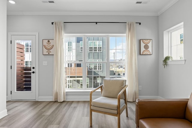 living area with plenty of natural light, light wood-type flooring, and crown molding