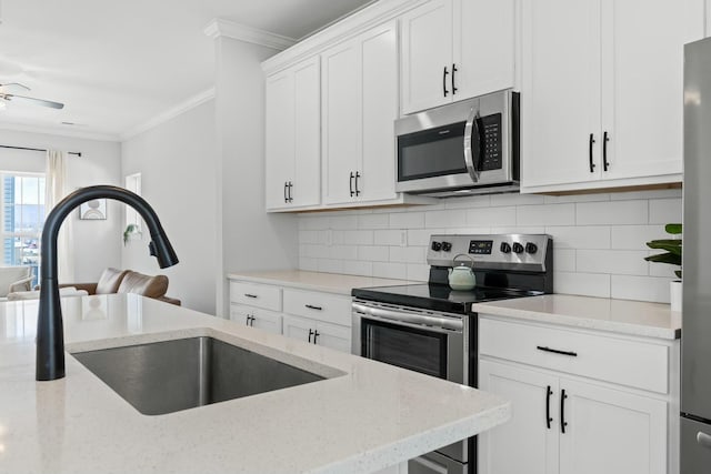 kitchen featuring white cabinetry, sink, stainless steel appliances, crown molding, and decorative backsplash