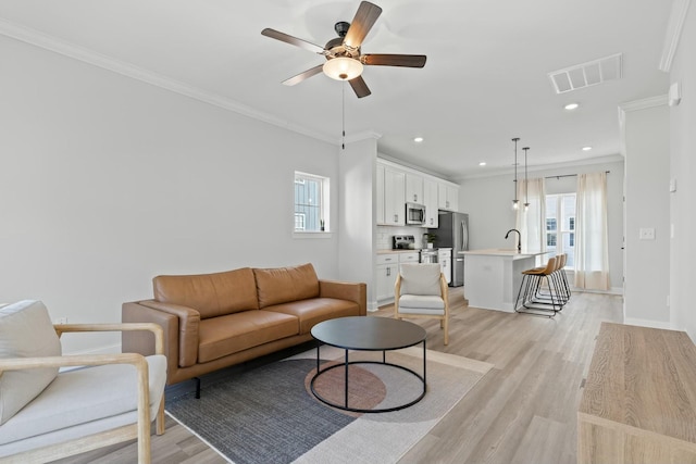 living room featuring a healthy amount of sunlight, light hardwood / wood-style floors, and crown molding