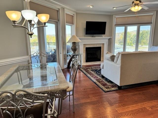 dining room with ceiling fan with notable chandelier, dark hardwood / wood-style floors, crown molding, and a fireplace