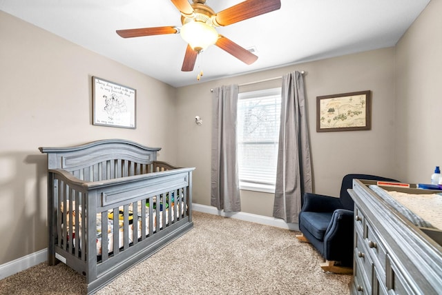 carpeted bedroom with ceiling fan and a nursery area