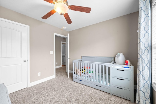 bedroom with ceiling fan, light carpet, and a nursery area