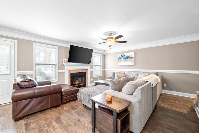 living room with hardwood / wood-style floors, ceiling fan, crown molding, and a tiled fireplace