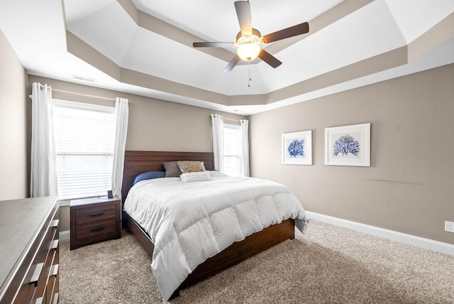 carpeted bedroom with a tray ceiling and ceiling fan