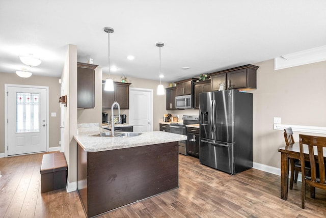 kitchen with dark brown cabinetry, sink, dark wood-type flooring, pendant lighting, and appliances with stainless steel finishes