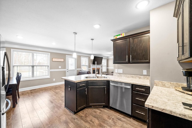 kitchen with stainless steel appliances, kitchen peninsula, crown molding, wood-type flooring, and decorative light fixtures