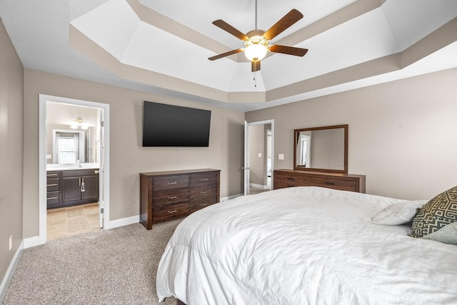 bedroom with connected bathroom, ceiling fan, sink, a tray ceiling, and light carpet