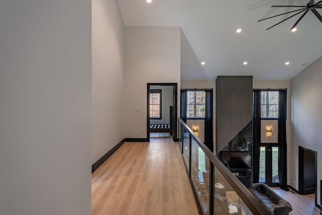 hall featuring light wood-type flooring and a towering ceiling