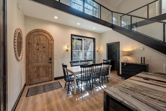 dining space featuring light hardwood / wood-style floors and a towering ceiling