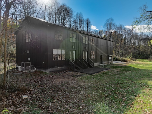 rear view of property featuring central AC and a yard