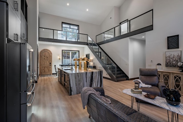 living room featuring a towering ceiling, sink, and light wood-type flooring