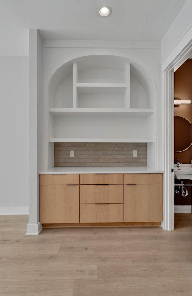 room details with tasteful backsplash, built in shelves, and hardwood / wood-style flooring