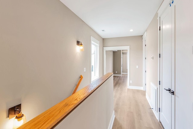 hall with an upstairs landing, recessed lighting, light wood-type flooring, and baseboards