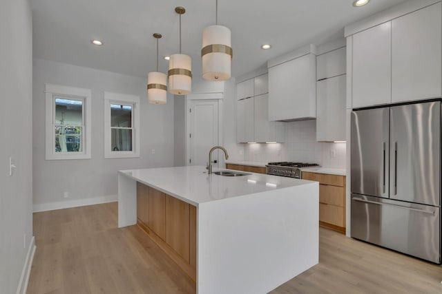 kitchen featuring sink, hanging light fixtures, an island with sink, white cabinets, and appliances with stainless steel finishes